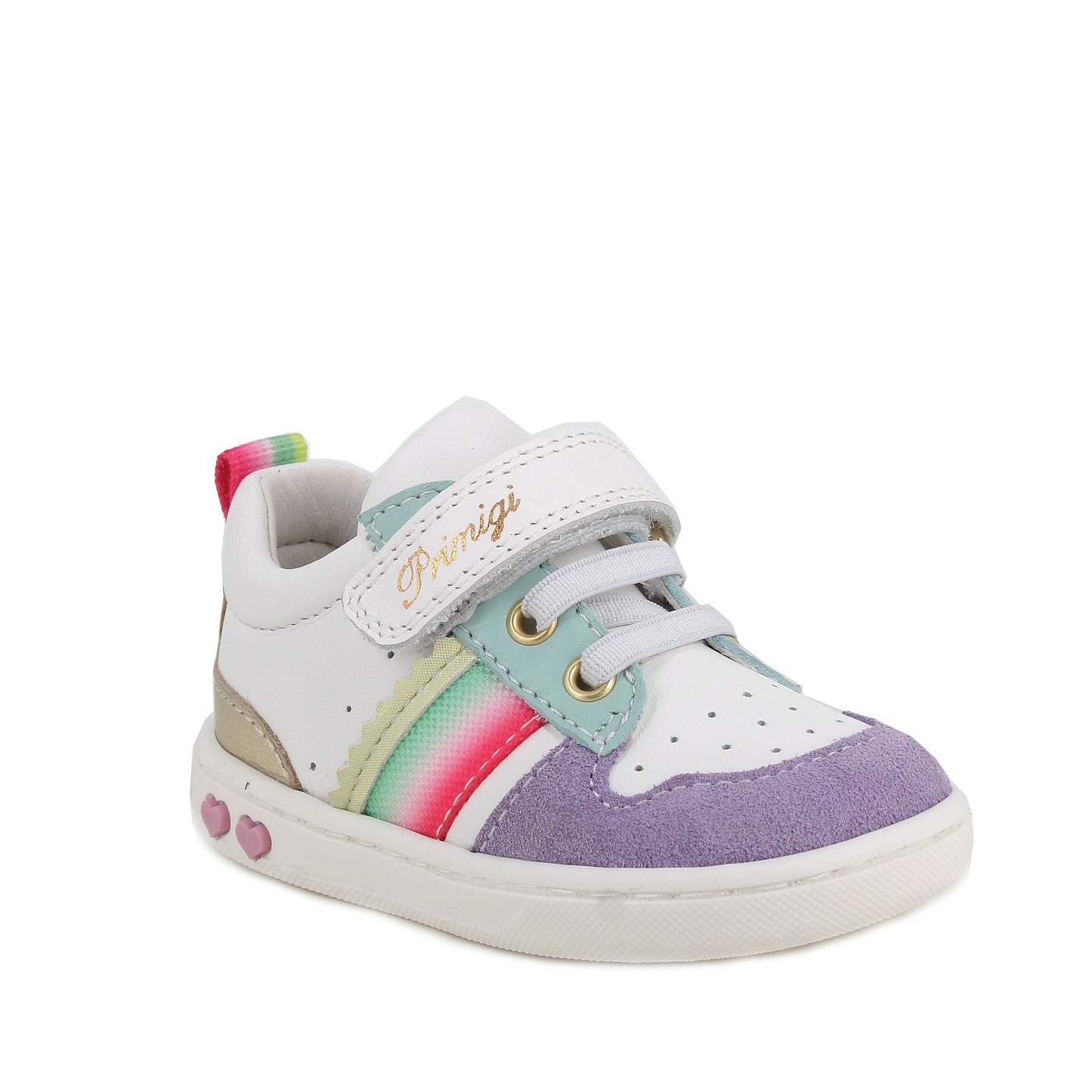 A girls casual trainer by Primigi, style Baby Like in white/iris with elastic laces and velcro strap. Rainbow stripe detail onside purple toe bumper pattern, and metallic design on heel. Two small pink love hearts on white sole. Angled front view