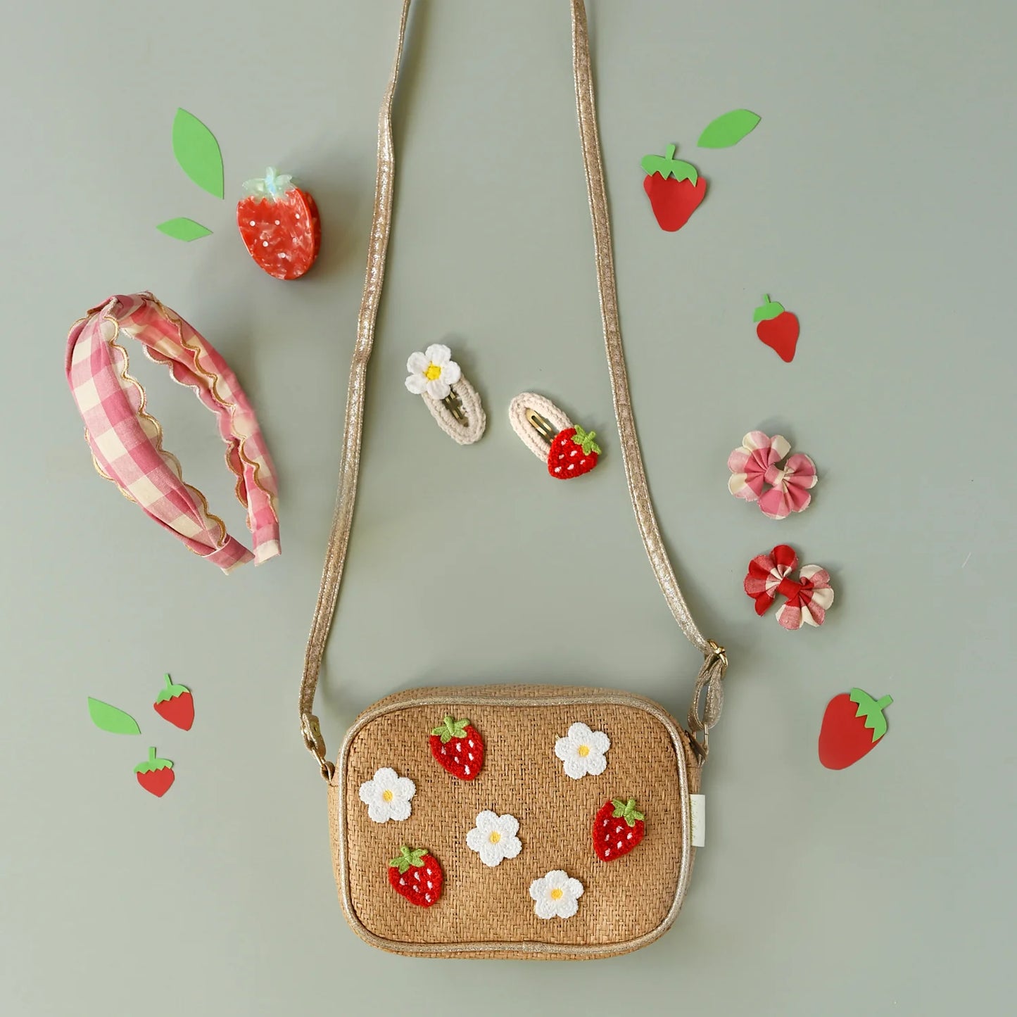 A selection of pink and white gingham and strawberry themed accessories by Rockahula, including a straw bag, headband and hair clips