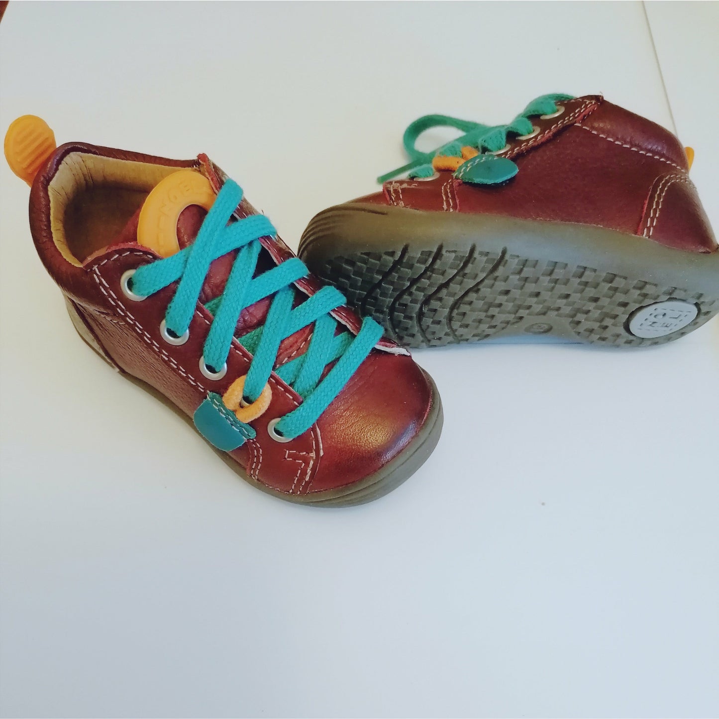 A boys boot by Noel, in burgundy leather with contrast blue laces. Right top view, left view of grey sole.