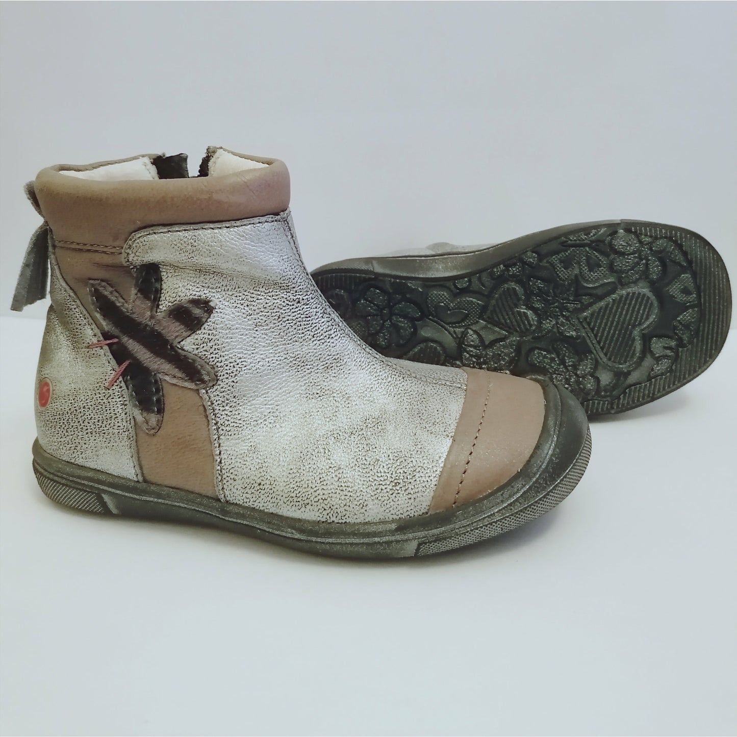 A girls boot by GBB, silver metallic with taupe leather panels and side detail, zip up with rubber toe. Right side view, left view of distressed sole.