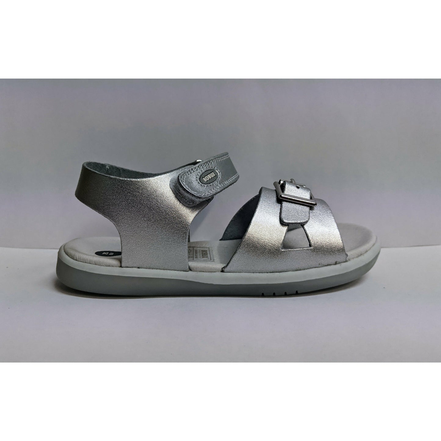 A girls open sandal by Bobux, style simple, in silver with velcro fastening. Right side view.,
