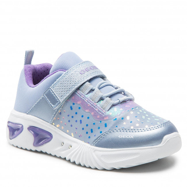 A girls light up trainer by Geox, style J Assister G, in sky blue with violet iridescent print. Velcro/ bungee lace fastening with a light up sole. Angled view.