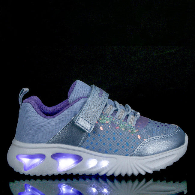 A girls light up trainer by Geox, style J Assister G, in sky blue with violet iridescent print. Velcro/ bungee lace fastening and a light up sole. Right side view showing lights.