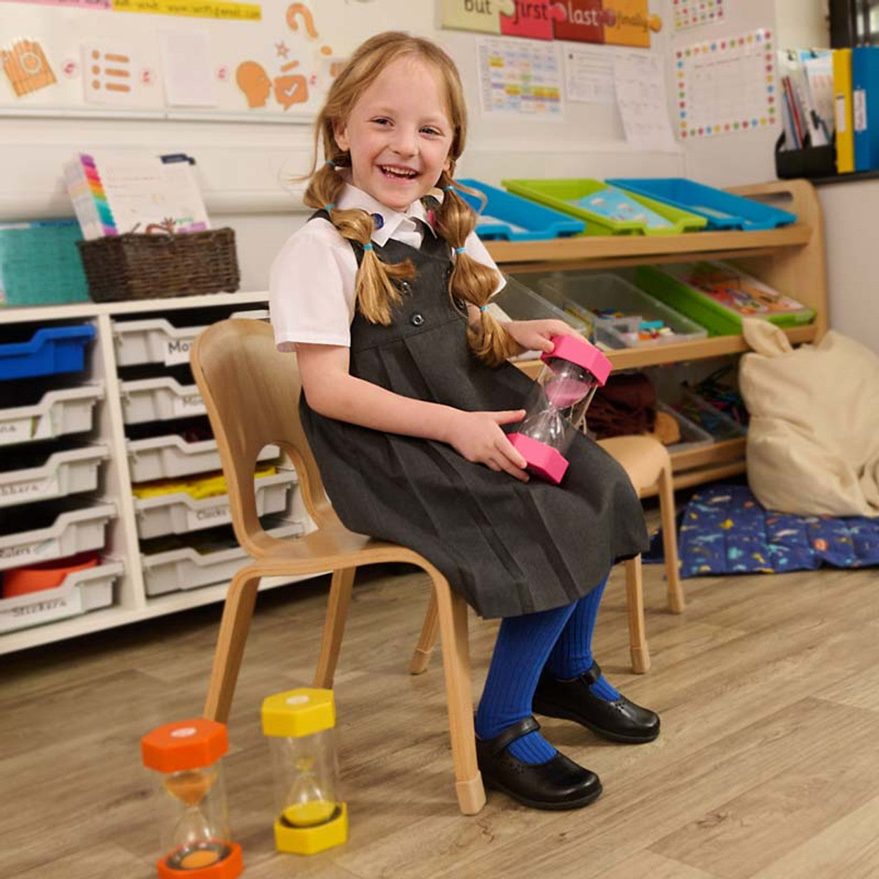 A girls T-bar school shoe by Start-Rite, style Charlotte in black leather with floral punch out detail and velcro fastening. Lifestyle image.