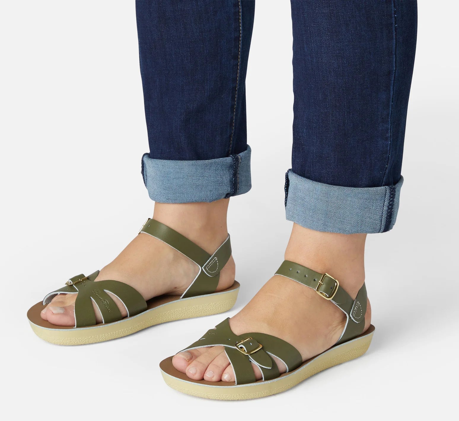 An adult sandal by Saltwater, style Boardwalk in olive with buckle strap. Side image of woman modelling the sandals