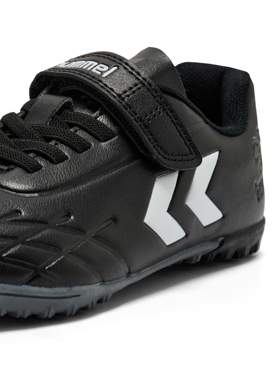 A astro turf football boot by Hummel, style Top Star Turf JR 228343-2267 in black with white trim with velcro fastening. Close up of angled left side view.