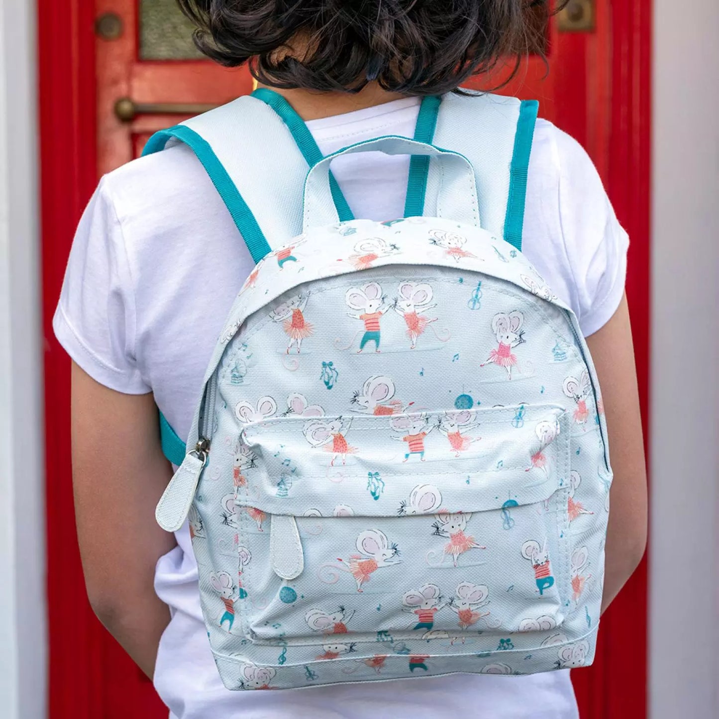 A childs backpack by Rex London, style Mimi and Milo, in blue with multi dancing mice print. Two compartments and zip fastening. Lifestyle image.