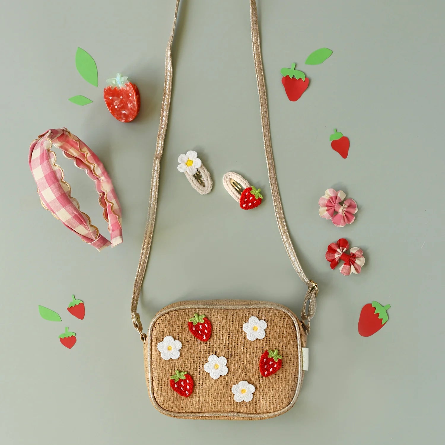 A selection of pink and white gingham and strawberry themed accessories by Rockahula, including a straw bag, headband and hair clips
