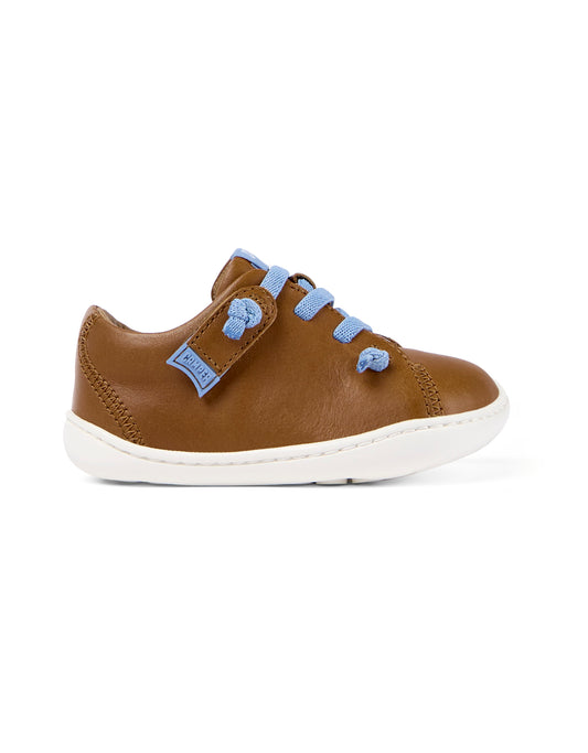 A boys/unisex shoe by Camper, style Peu in brown with blue elastic laces and a velcro tab. Right side view..