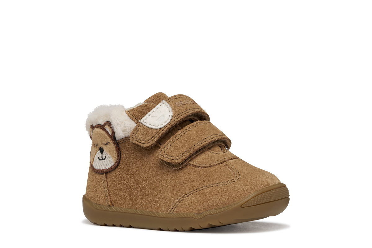 Geox suede ankle boot in brown, with two Velcro straps, bear detailing, fur lining and a tan rubber sole. Angled front view of right shoe.