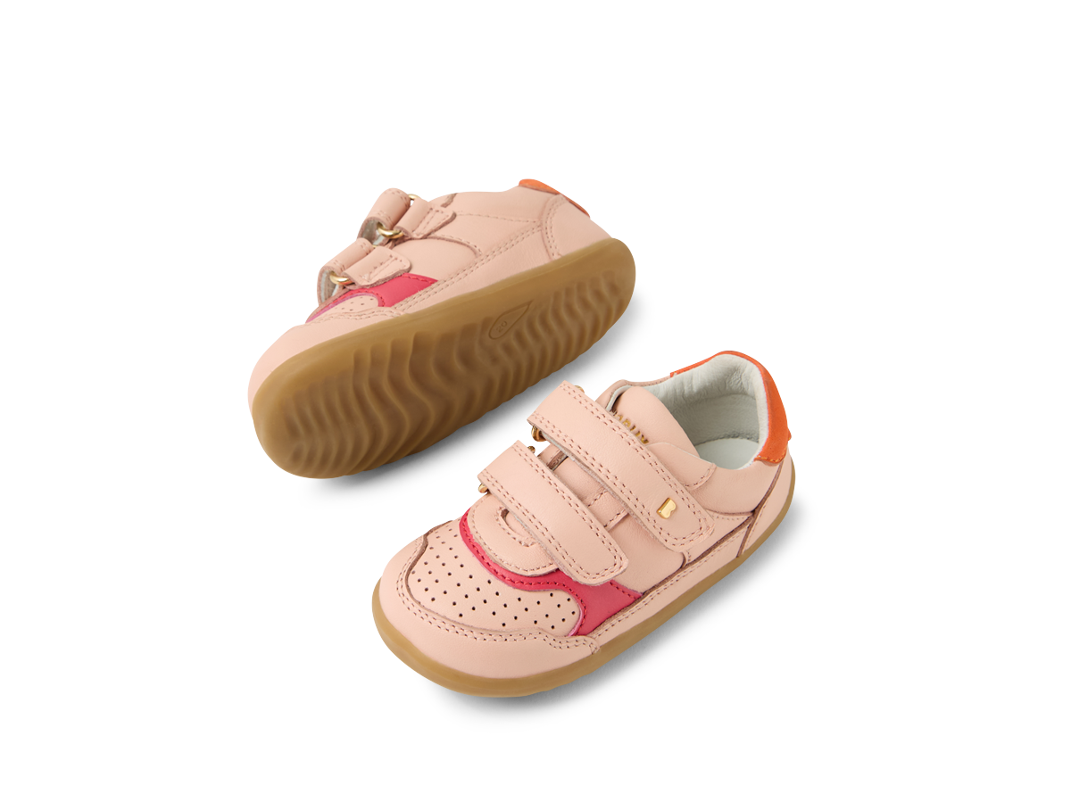 A girls casual shoe by Bobux, style Hunter in pink with bright pink and orange trim and velcro fastening. Angled view of a pair.