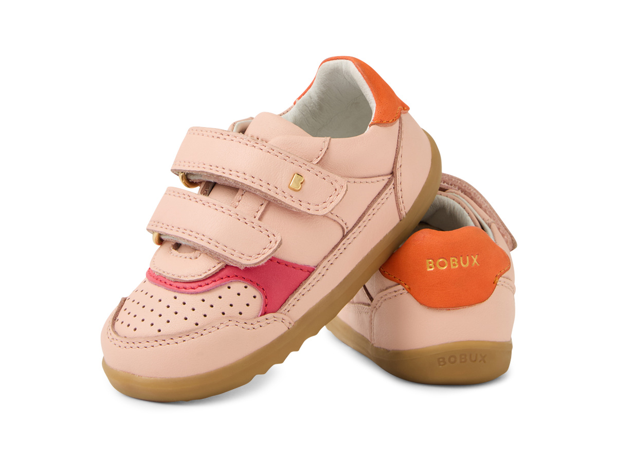 A girls casual shoe by Bobux, style Hunter in pink with bright pink and orange trim and velcro fastening. Angled view of a pair showing Bobux in gold.