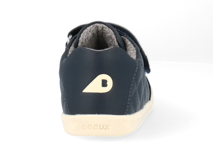 A boys casual shoe by Bobux, style Stitch, in navy leather ,with stitch detail and double velcro fastening. Close up of logo on back of shoe.