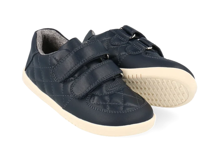 A pair of boys casual shoes by Bobux, style Stitch, in navy leather ,with stitch detail and double velcro fastening. Angled view.
