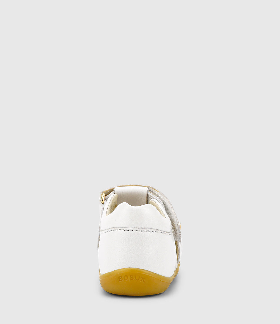 A unisex sandal by Bobux, style Cross Jump in white with velcro strap and light brown sole. Back view with logo on sole