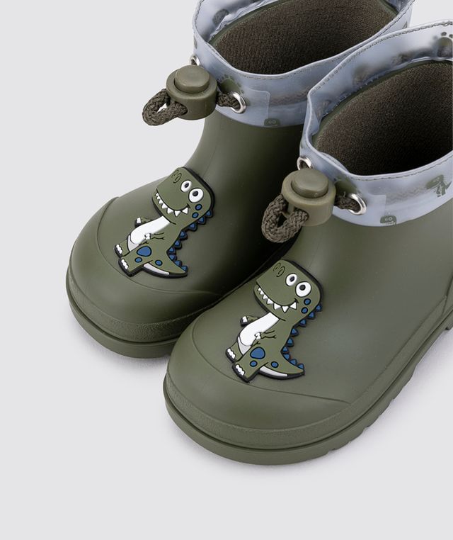 A pair of unisex wellies by Igor, style W10323-042 Mendi Dino, in Khaki with dino detail and toggle fastening. Angled left sided view of a pair.