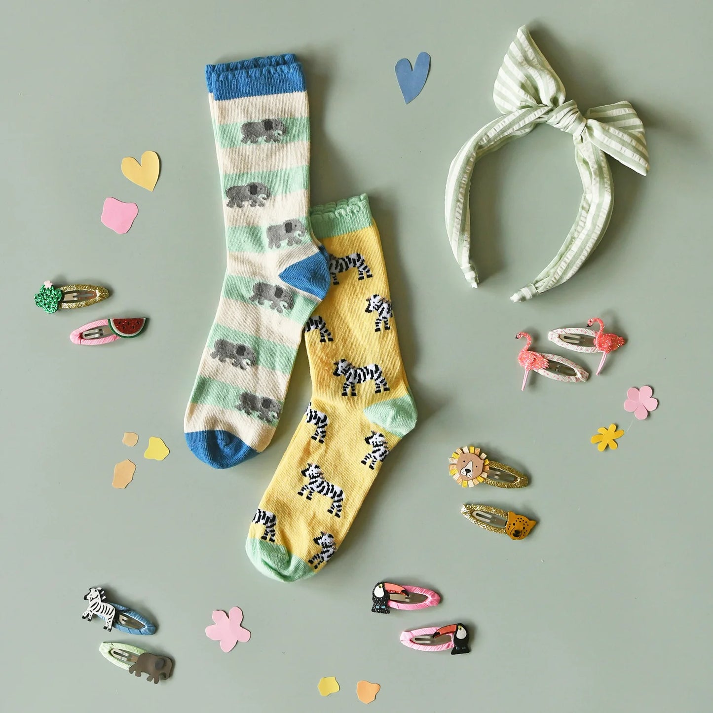 Two pairs of children's socks with animal patterns by Rockahula, a headband, and hair accessories on a gray background.
