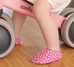 A pair of girls non-slip swim shoes by Slipfree, style Dream Junior, in pink heart print. Lifestyle image.