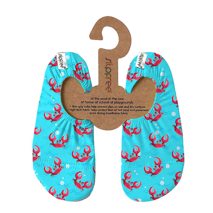 A pair of swim shoes by Slipfree, style Dalyan in blue with crab design, hanging on cardboard hanger