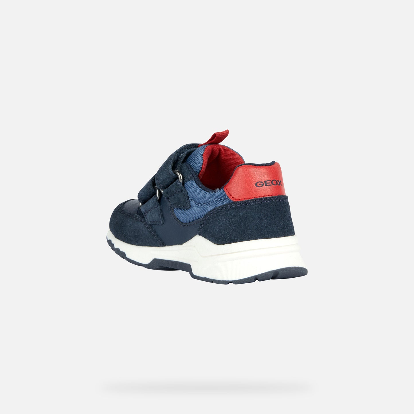 A casual sports trainer by Geox, style B Pyrip Boy, in navy suede/ other material with red heel and tab and light grey star outline on the side. Double velcro fastening. Inner side angled view.