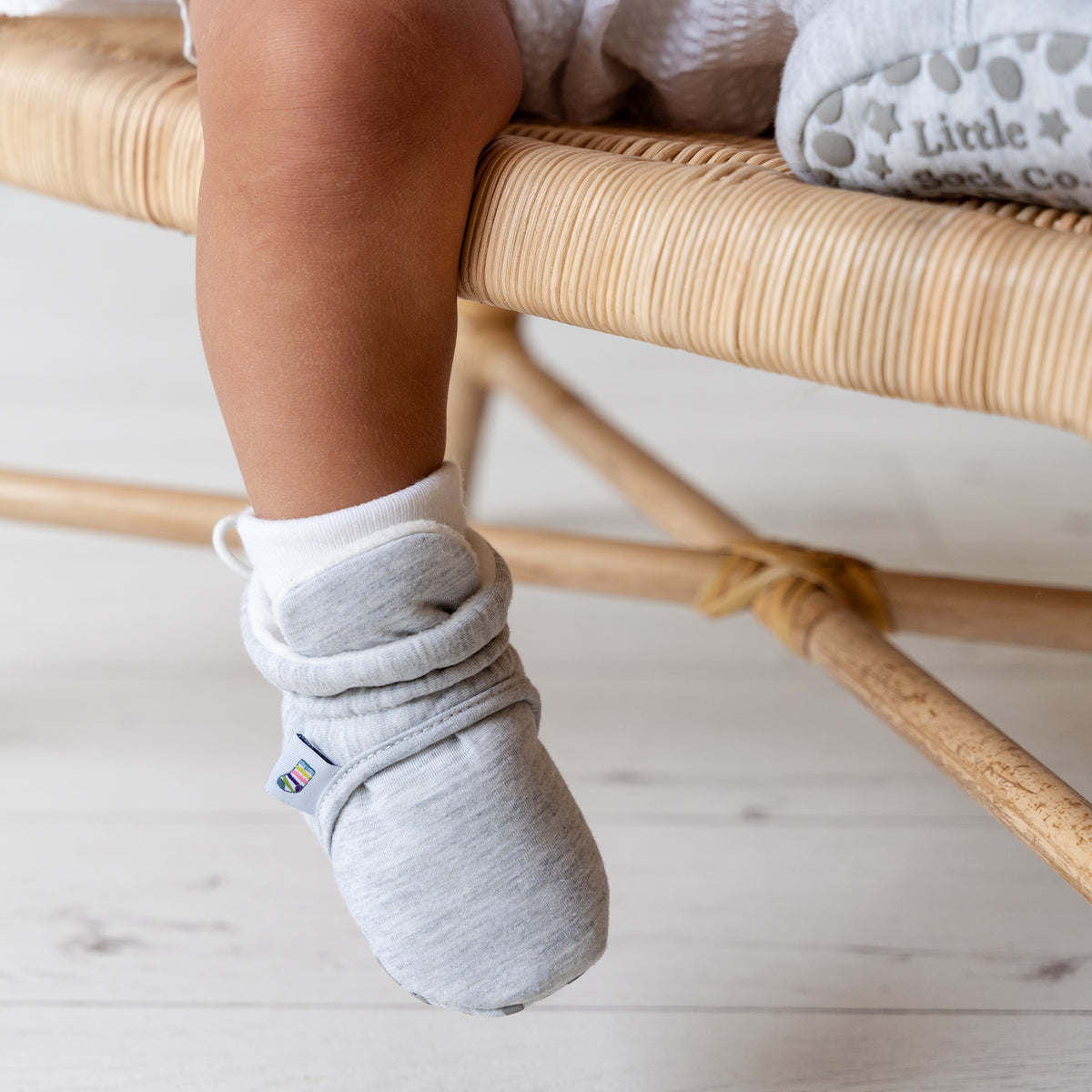 Grey bootie non slip slipper with pull toggle for a perfect fit for babies. Lifestyle foot view.