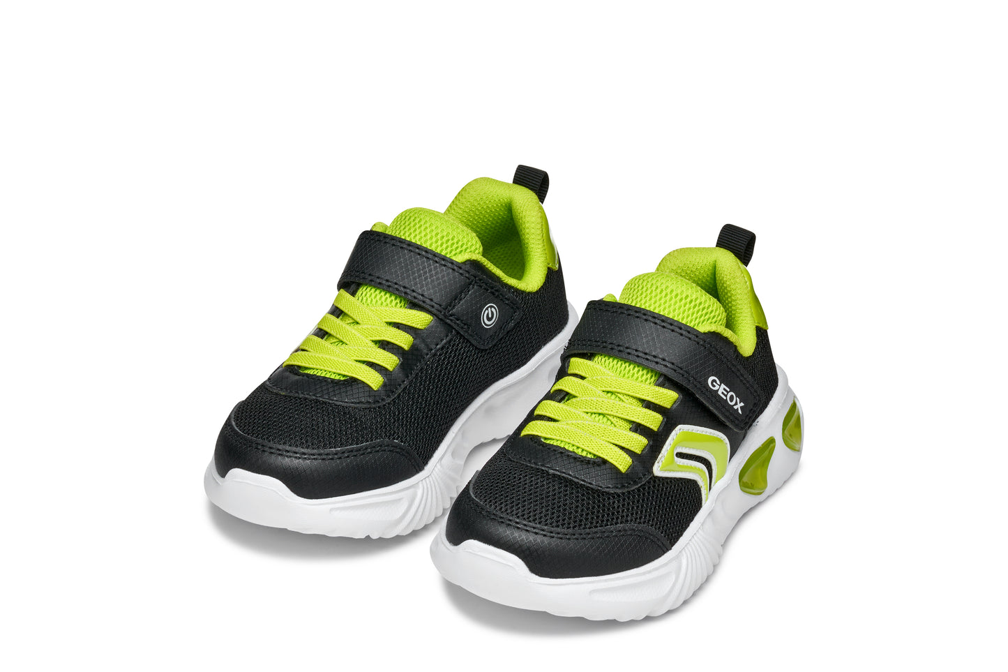 A boys trainer by Geox, style Assister, in black/lime with velcro strap and green laces. Angled view of a pair.