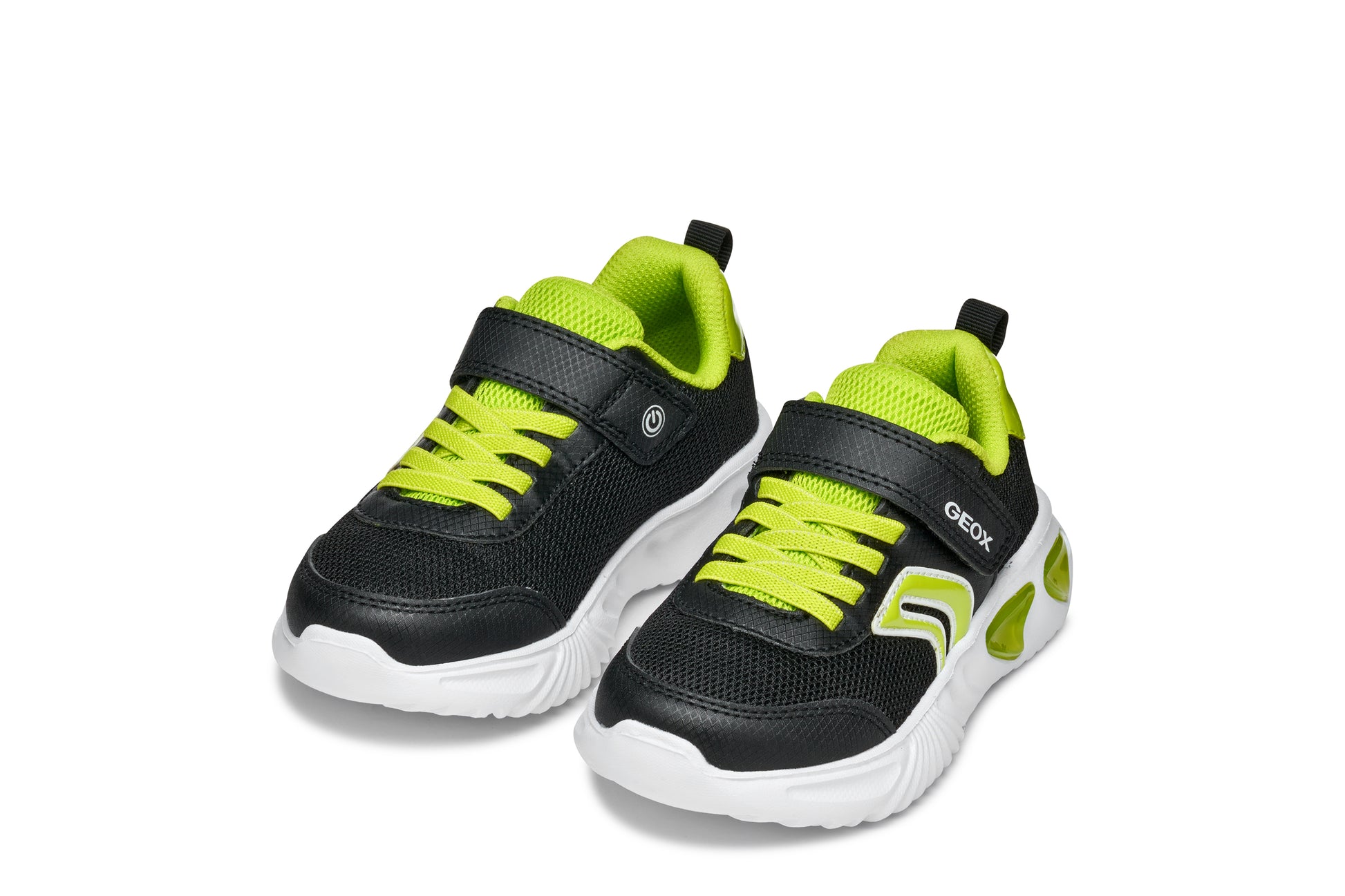 A boys trainer by Geox, style Assister, in black/lime with velcro strap and green laces. Angled view of a pair.