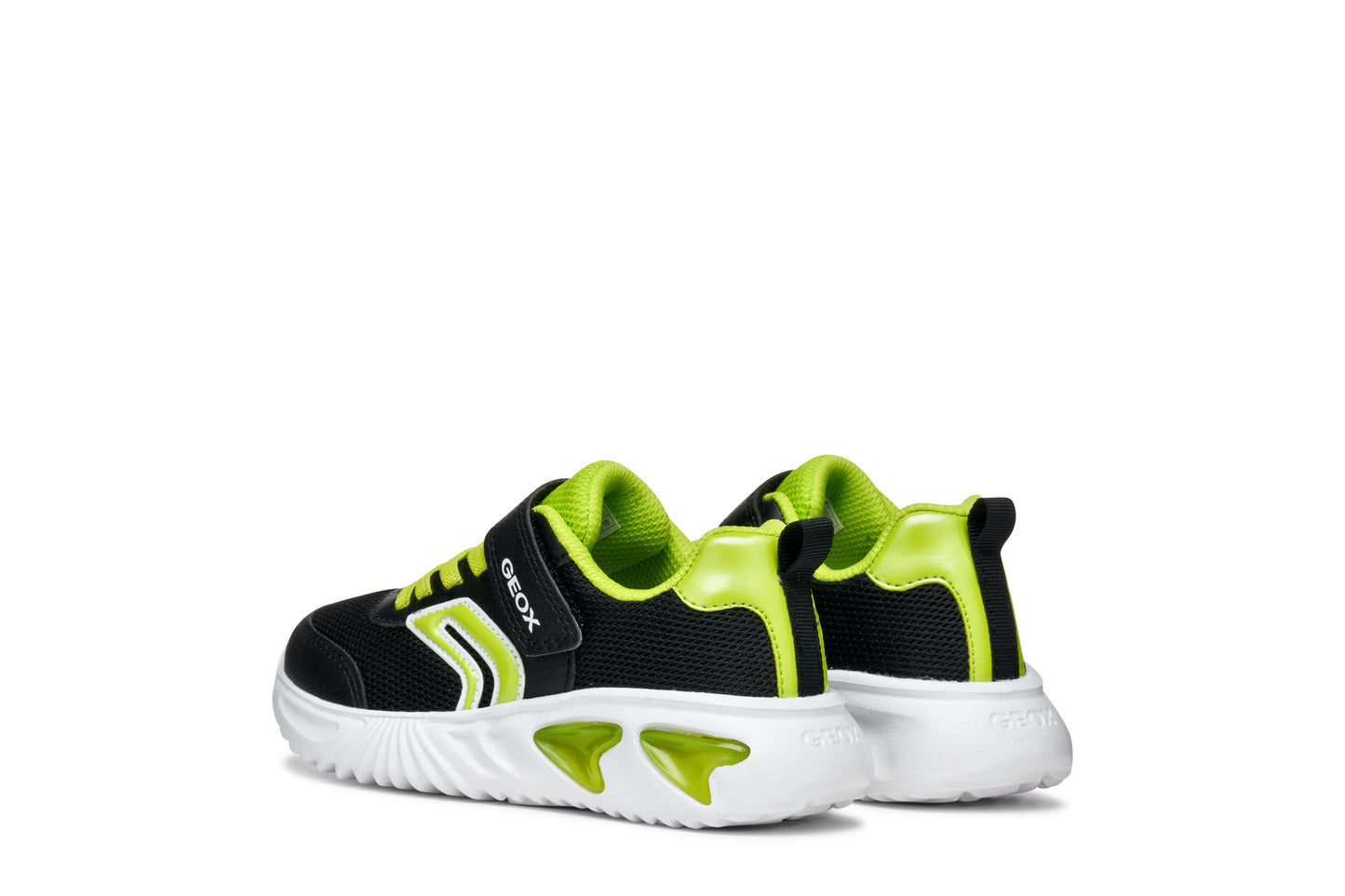 A boys trainer by Geox, style Assister, in black/lime with velcro strap and green laces. Angled left side view of a pair.