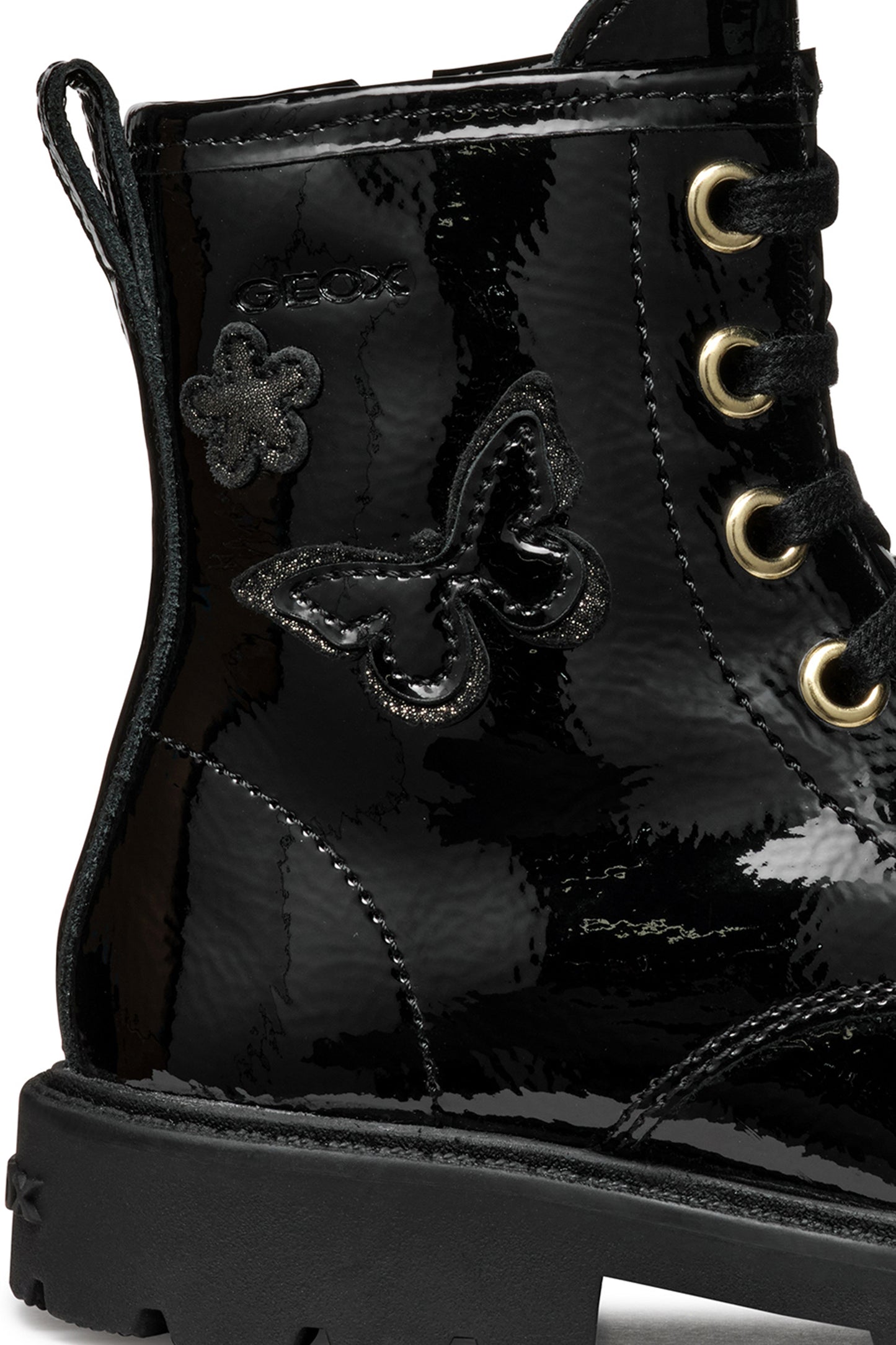 A girls combat style boot by Geox, style J56EXA Shaylax, in black patent  leather with butterfly detail. Lace and zip fastening. Close up of butterfly detail. Right side view.
