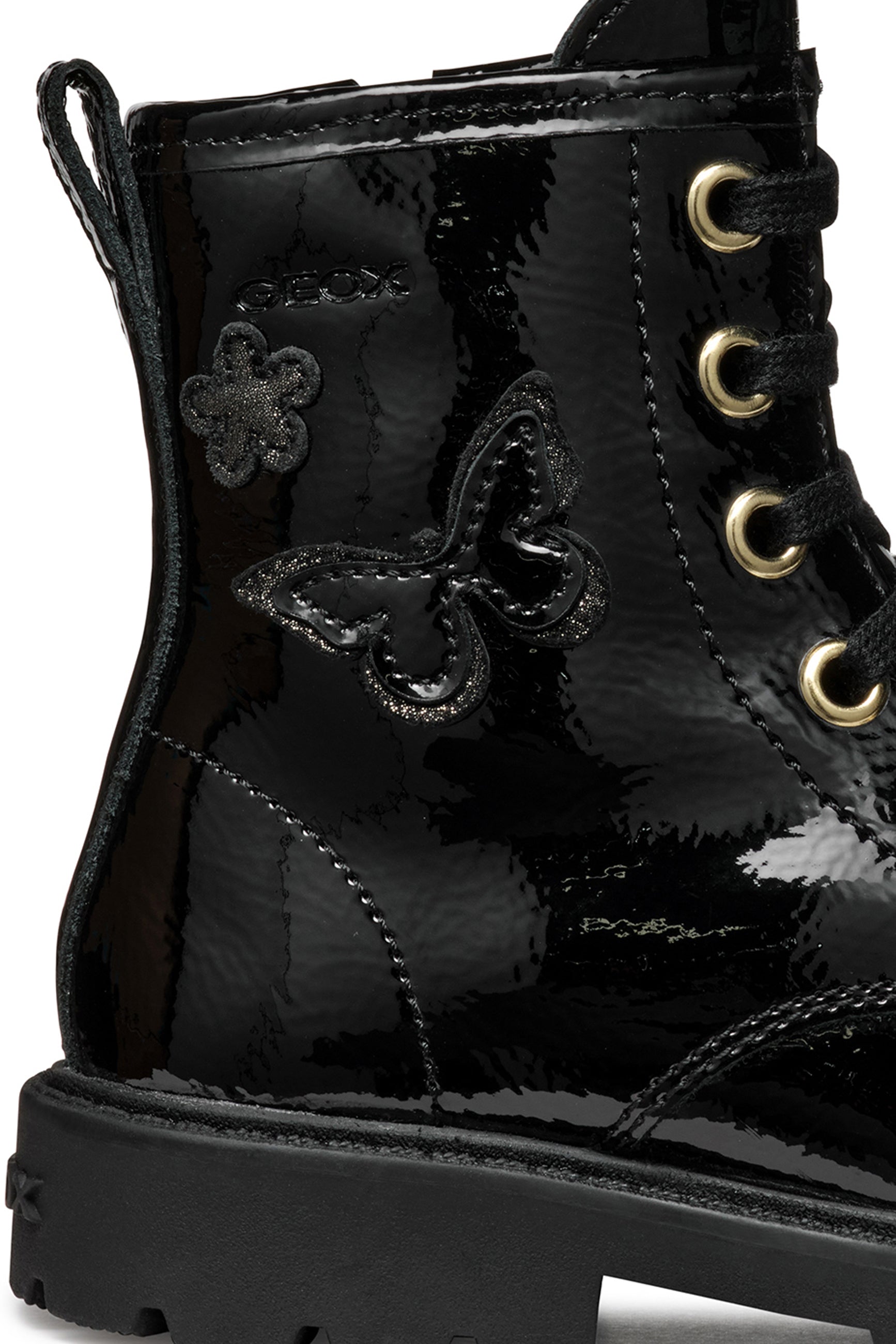 A girls combat style boot by Geox, style J56EXA Shaylax, in black patent  leather with butterfly detail. Lace and zip fastening. Close up of butterfly detail. Right side view.