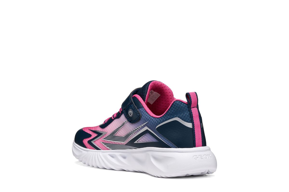 Geox girls trainer in the style Assister in navy, pink and white with a Velcro strap, lights and a white sole. Angled back view of right shoe.