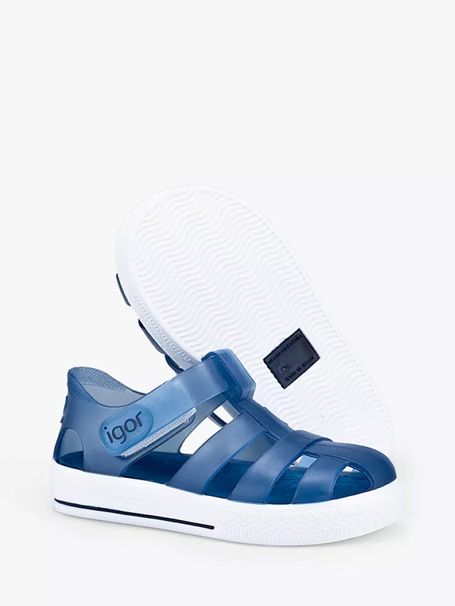 A unisex closed toe jelly shoe by Igor, style Star, in marino blue and white with velcro fastening. Angled view showing right shoe and left sole.