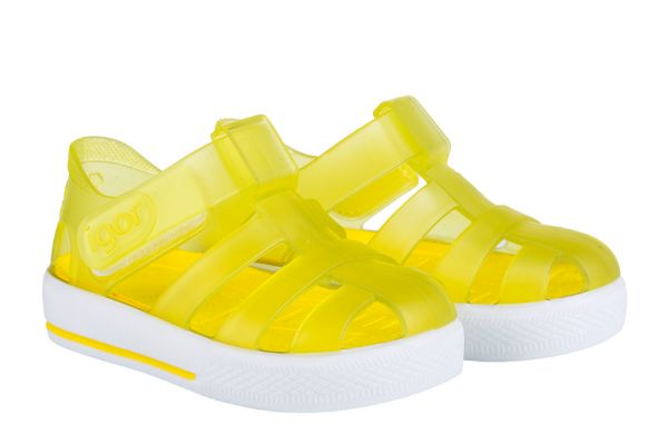 A pair of unisex closed toe jelly shoes by Igor, style Star, in amarillo yellow and white with velcro fastening. Angled view of right side.