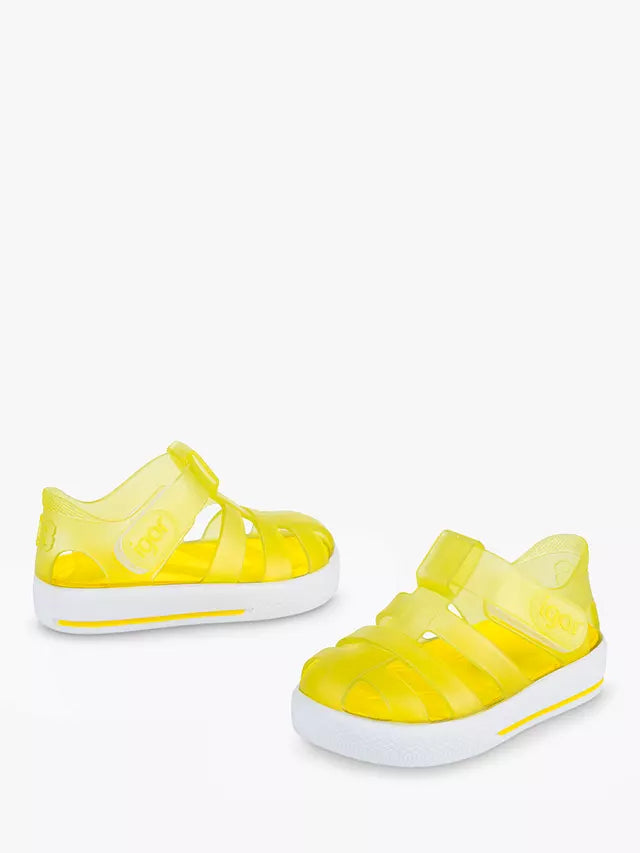 A pair of unisex closed toe jelly shoes by Igor, style Star, in amarillo yellow and white with velcro fastening. Angled view.