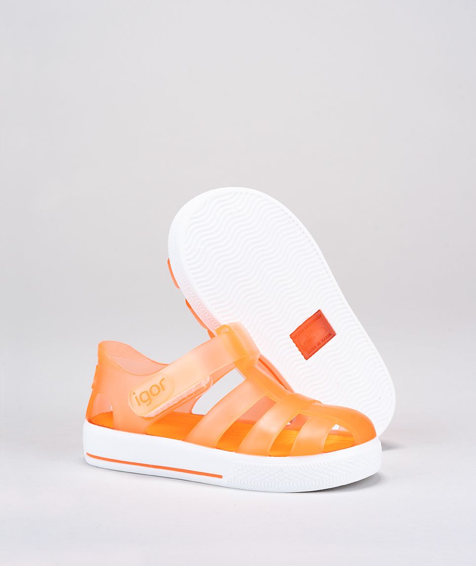 A unisex Jelly shoe by Igor, style Star in orange with a white sole, velcro fastening. Right side view, left sole view.