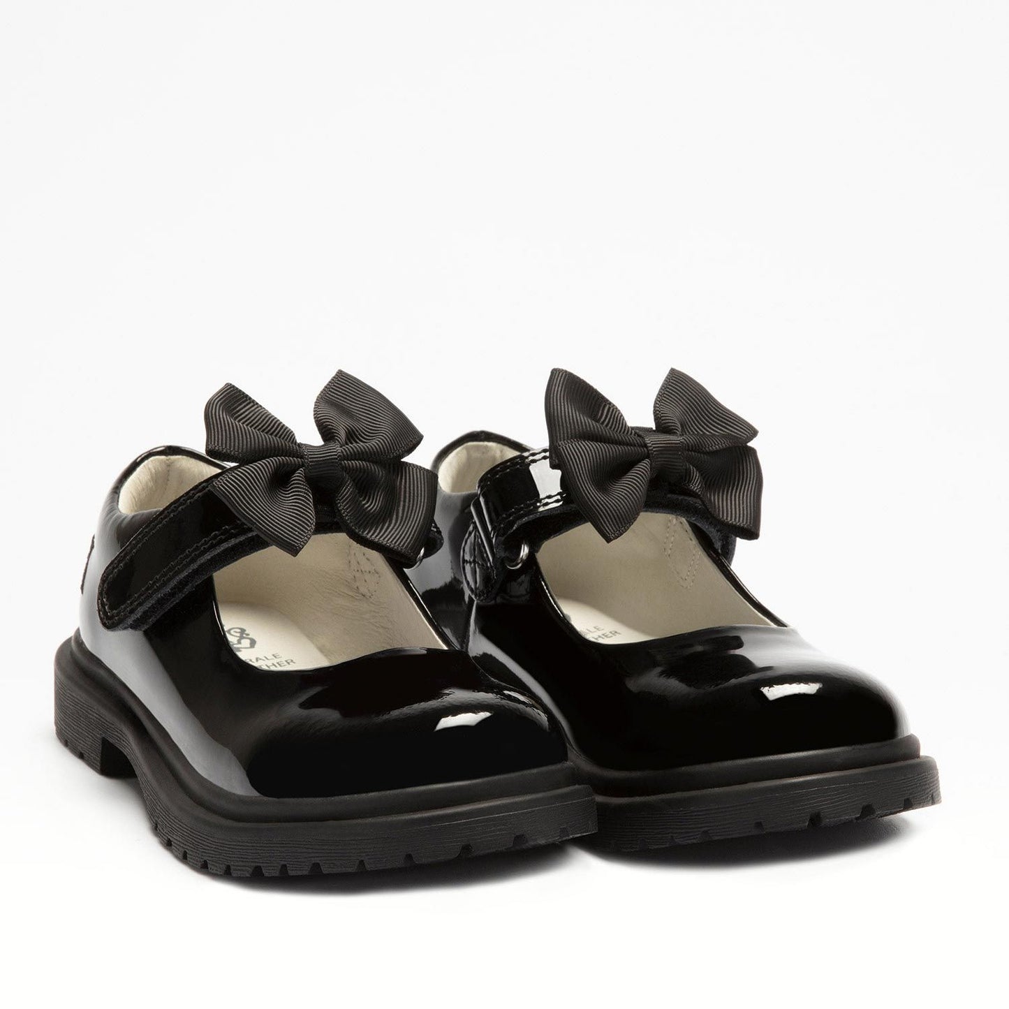 A pair of girls chunky Mary Jane school shoes by Lelli Kelly, style LK8661 Maisie, in black patent leather with velcro fastening and detachable black fabric bow. Angled view.