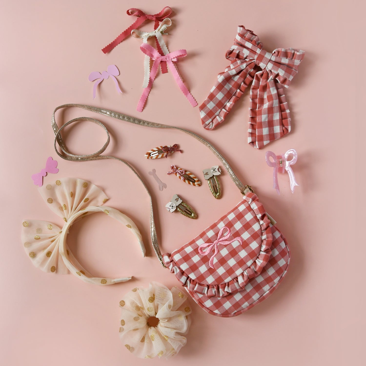 Collection of children's hair accessories by Rockahula including bows and a small bag on a pink background