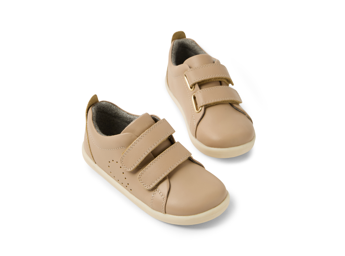 A pair of  unisex casual shoes by Bobux, style Grass Court, in taupe leather with double velcro fastening. Angled view of a pair.