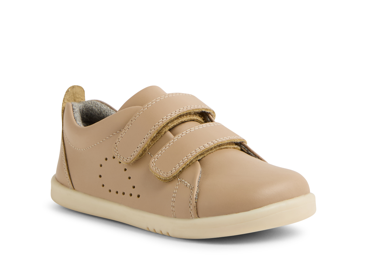 A unisex casual shoe by Bobux, style Grass Court, in taupe leather with double velcro fastening. Angled view.