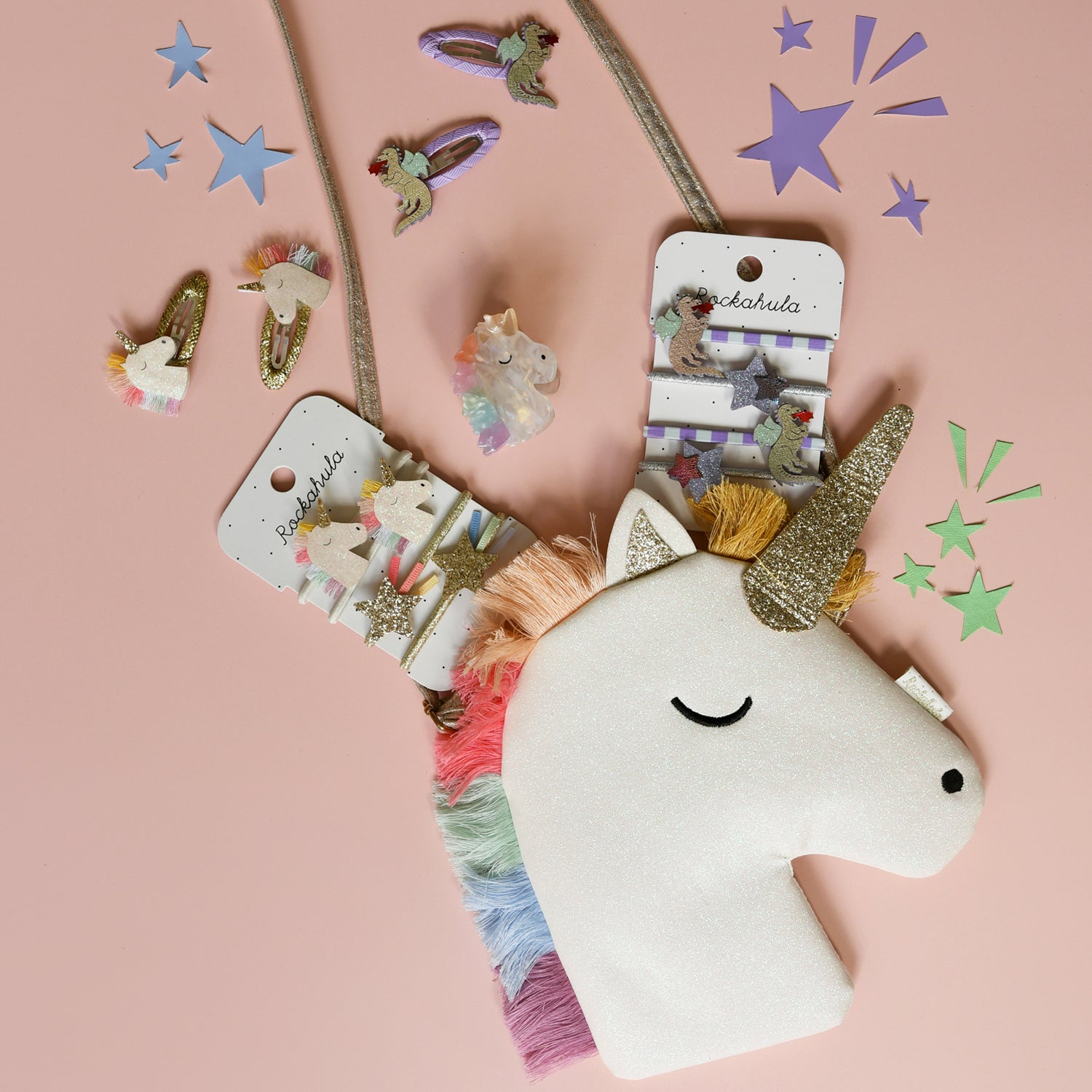 Unicorn-shaped hair accessories and bag by Rockahula with packaging on a pink background