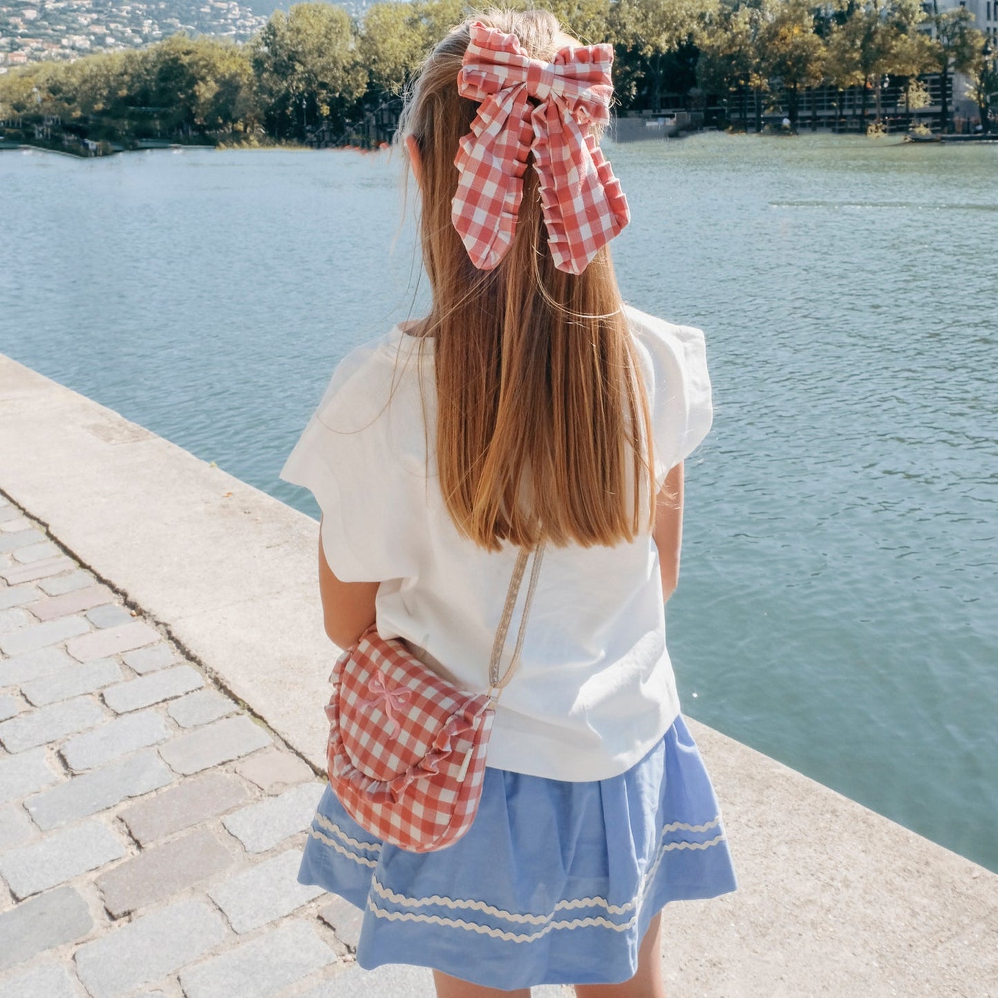 Pink gingham bow hair clip by Rckahula worn by girl with long hair.