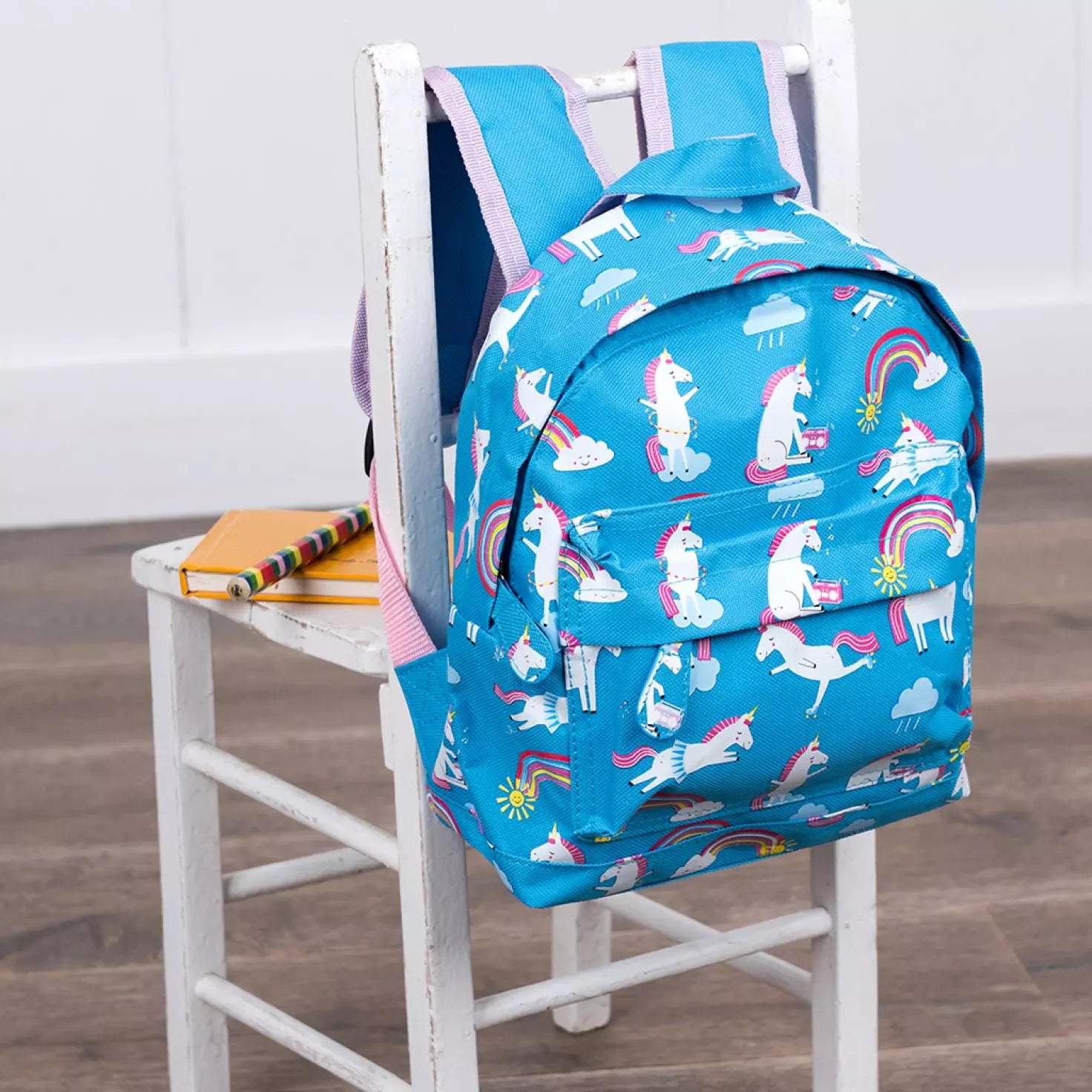 A child's backpack by Rex London, style Magical Unicorn,in blue with white multi unicorn and rainbow print, two compartments and zip fastenings. Lifestyle view.
