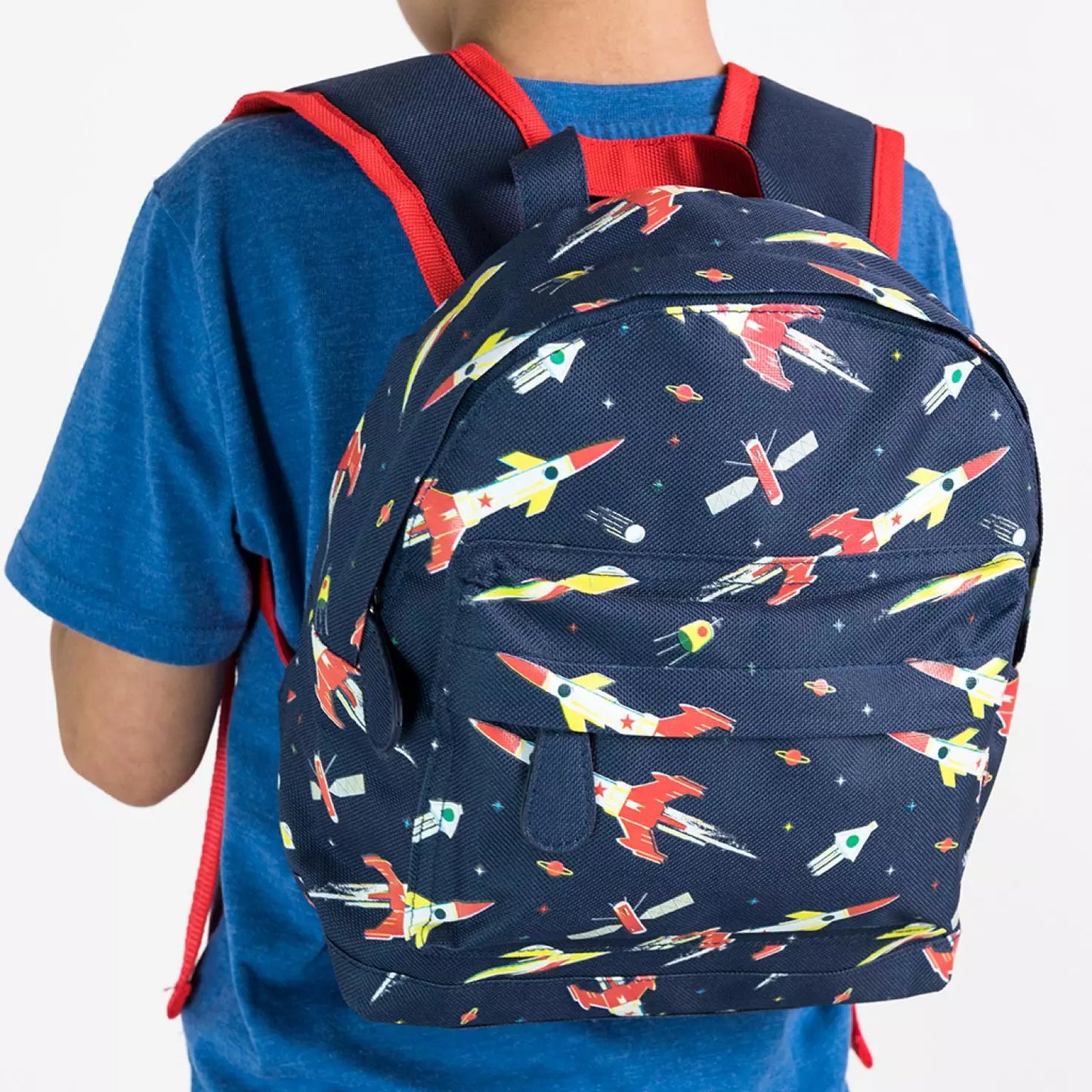 A childs backpack by Rex London, style Space Age, in blue with multi rocket print, two compartments and zip fastenings. Lifestyle image.