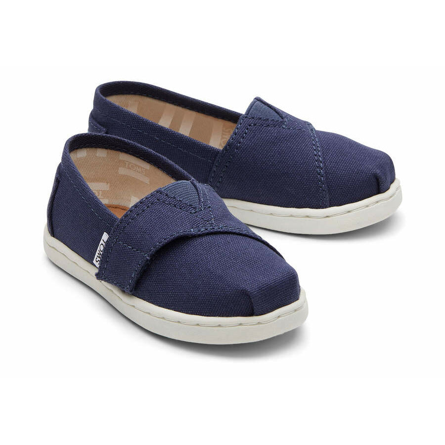 A unisex canvas shoe by TOMS, style Alpargata, in navy with a velcro strap. Front view of a pair.