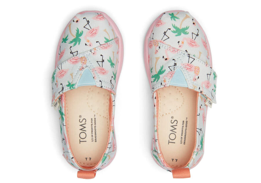 A girls canvas shoe by TOMS, style Alpargata Flamingo, in soft blue flamingo print with velcro fastening. Top view of a pair.