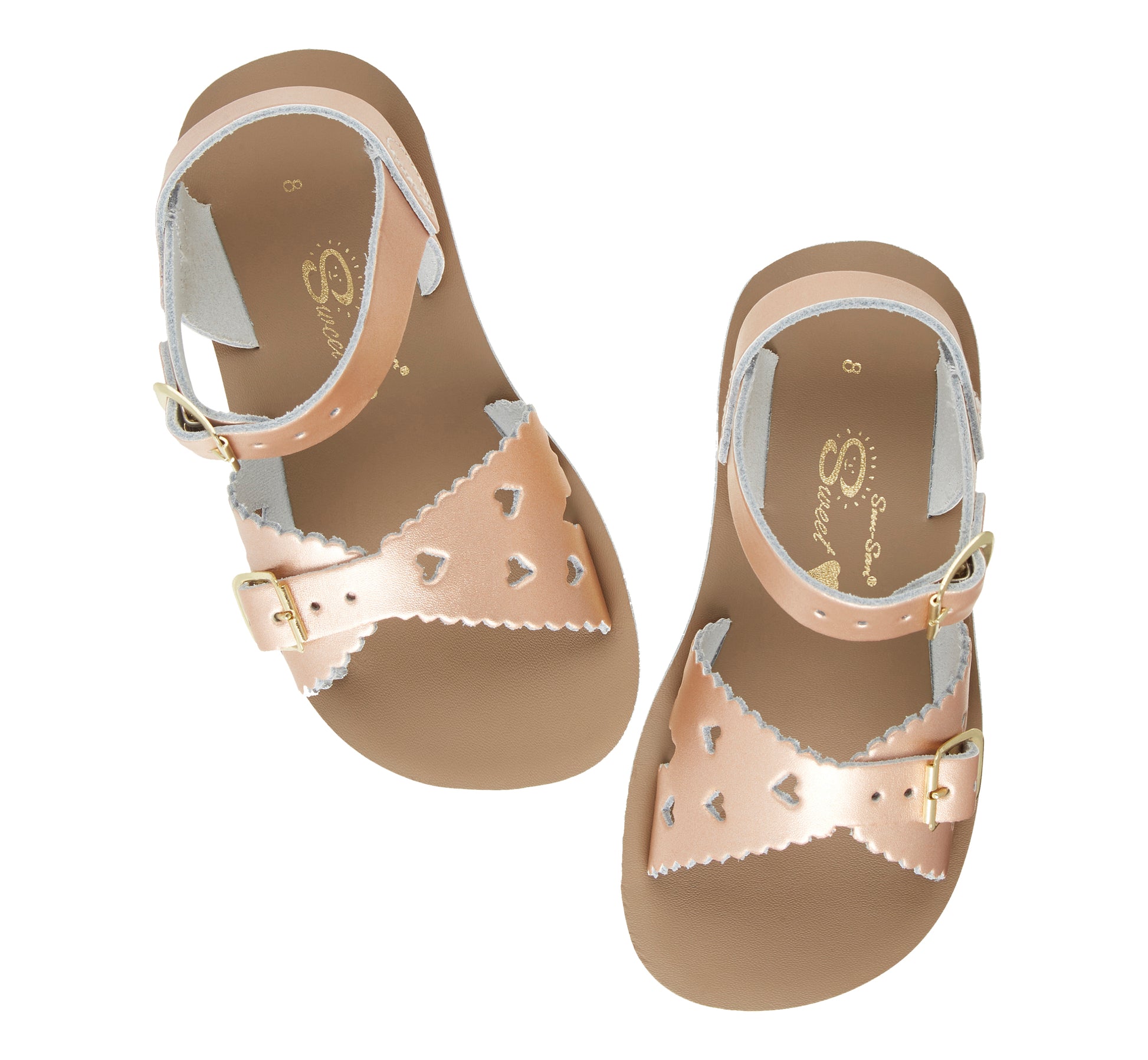 A girls sandal by Salt Water Sandal in rose gold with double buckle fastening across the instep and around the ankle. Featuring scallop edge and punched out heart detail. Top view.