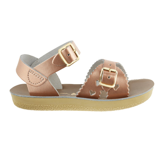 A girls sandal by Salt Water Sandal in rose gold with double buckle fastening across the instep and around the ankle. Featuring scallop edge and punched out heart detail. Right Sideview.