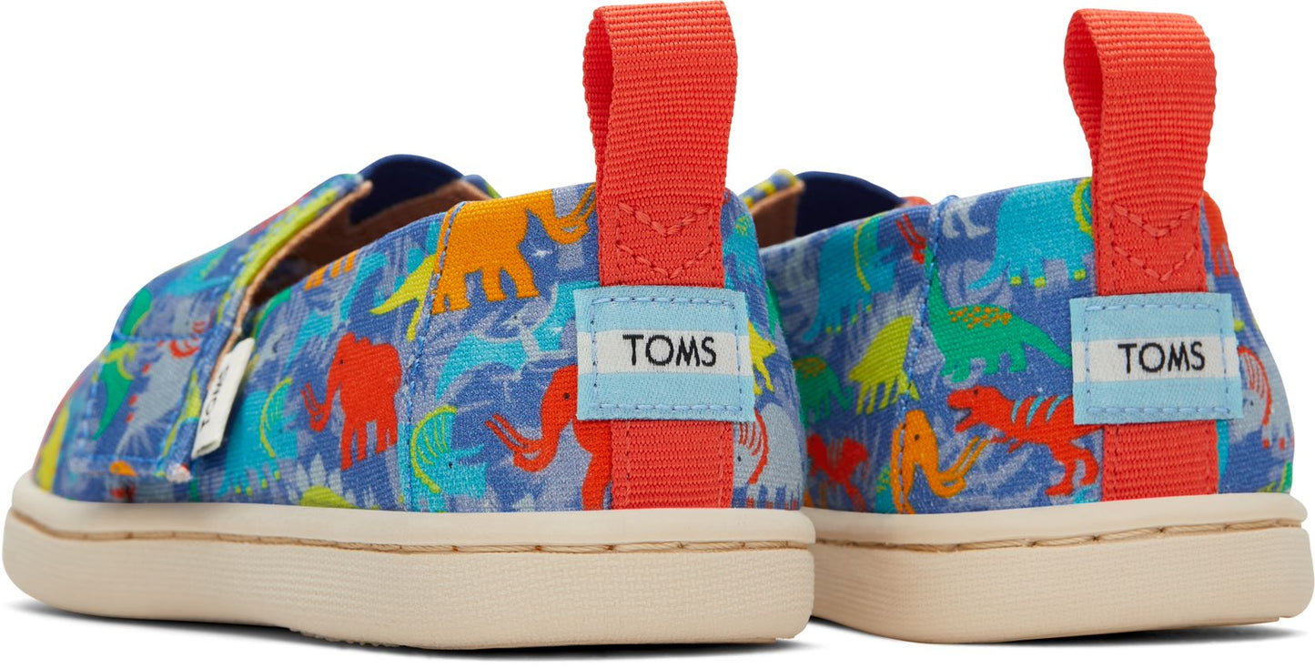 A boys canvas shoe by Toms, style Alpargata Dinos, in dinosaur print with velcro fastening. Back view of a pair.