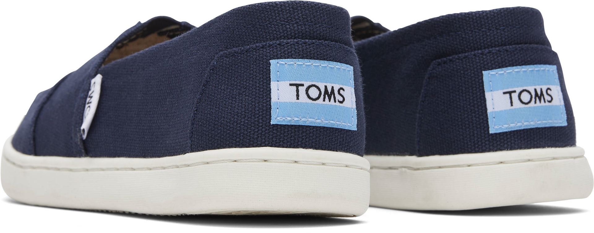 A unisex canvas shoe by TOMS, style Alpargata, a slip on in navy. Back view of a pair.