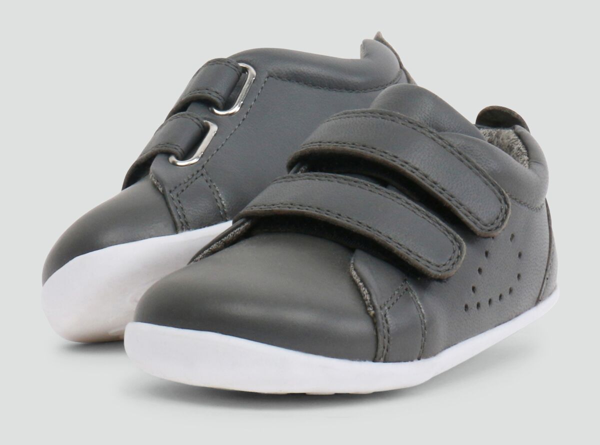 A pair of boys casual trainers by Bobux, style Grass Court,in grey with double velcro fastening. Right side view.